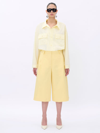 Person wearing a light yellow short with sunglasses on a white background