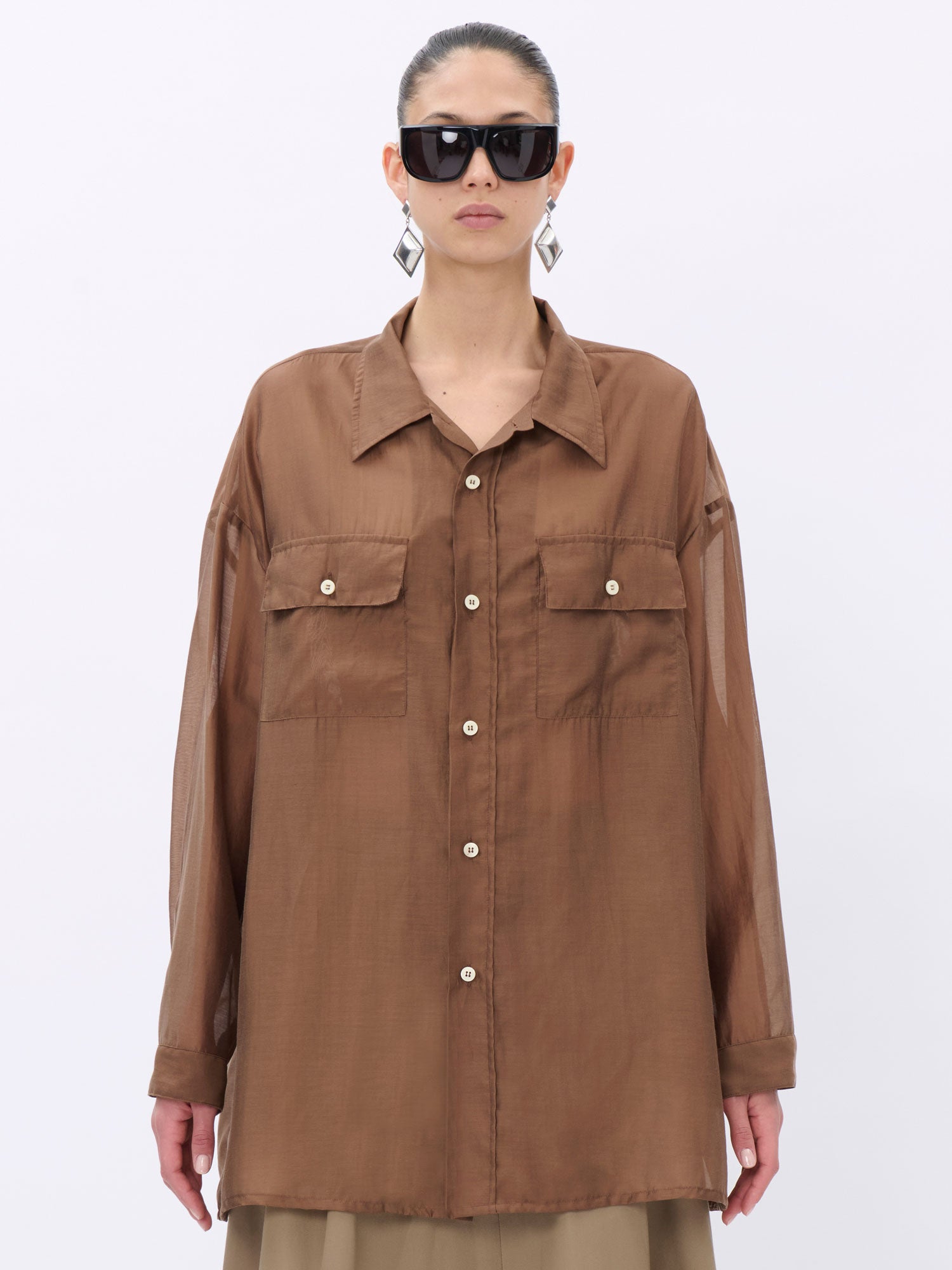 Person wearing a brown button-up shirt on a white background