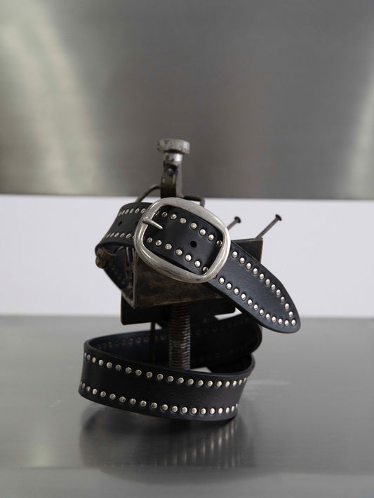 Black leather belt with silver studs on a reflective surface