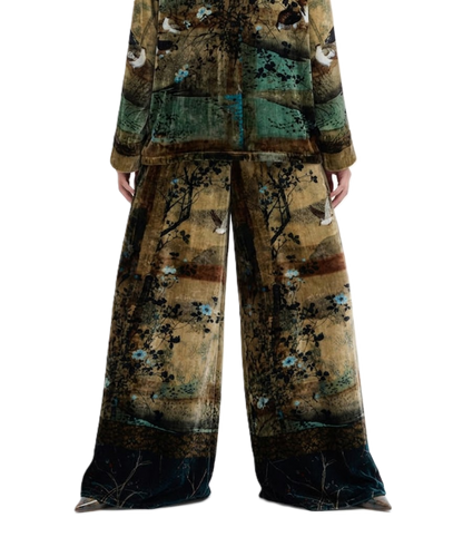A two-piece matching pajama set featuring a wide-leg pants and long-sleeve top, both printed with an artistic, textured landscape design in earthy brown, teal, and black tones with small bird motifs.