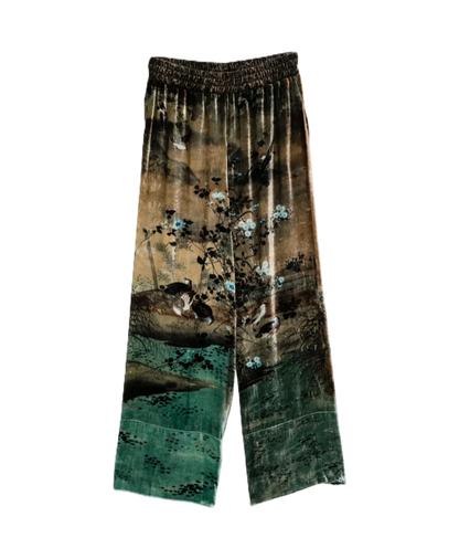 A pair of wide-leg cropped pants featuring a vintage-style landscape print with a brown and green color palette, blue blossoms, and birds, finished with an elastic waistband.