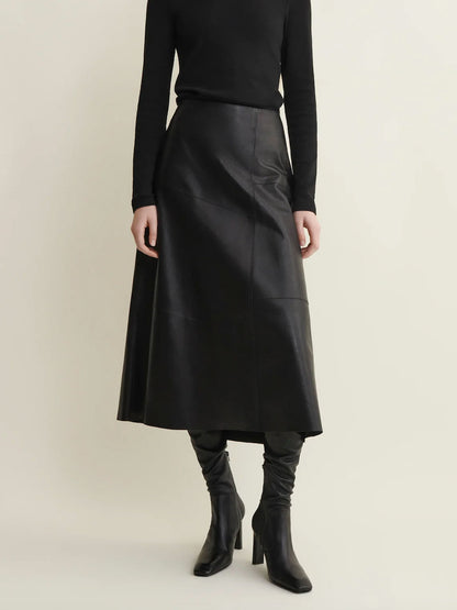 Person wearing a black leather skirt and black boots on a beige background