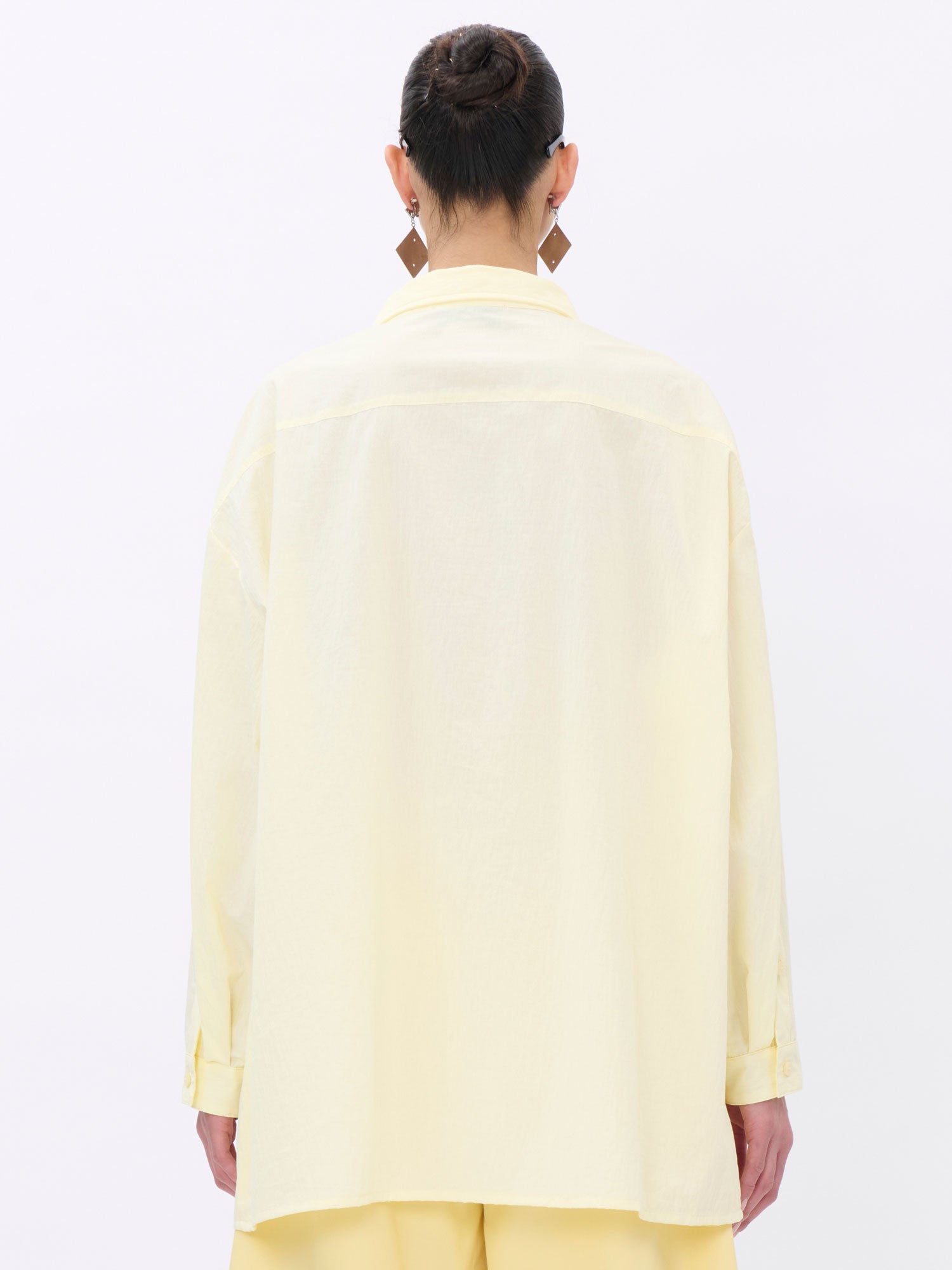 Person wearing a light yellow shirt on a white background