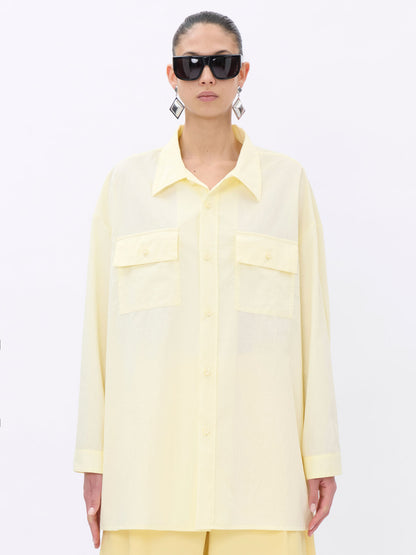 Person wearing a light yellow shirt and sunglasses on a white background