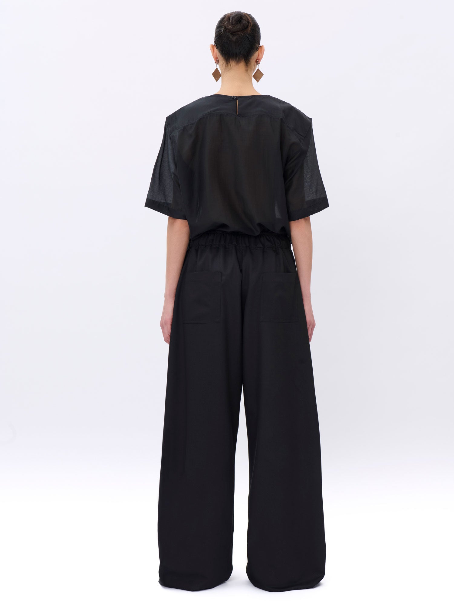 Person wearing a black outfit with wide-leg pants on a white background