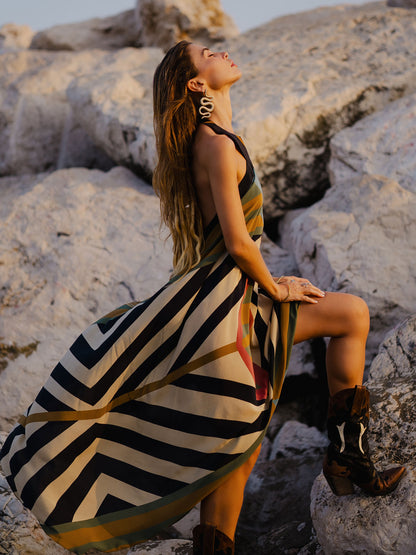 Woman in a striped dress sitting on rocks with a scenic background