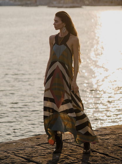 Woman in a colourful geometrical dress standing by a body of water